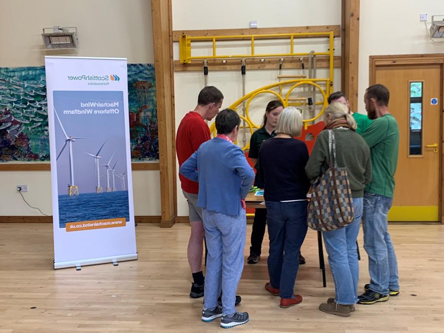 Members of the community gather around MachairWind team booth to learn about the project